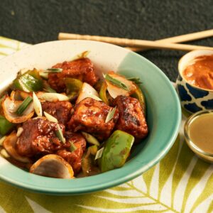 A vibrant bowl of stir-fried tofu with vegetables, garnished with green onions. Perfect for an appetizing meal.