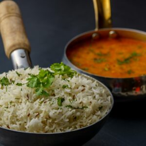 A savory dish of Indian dal with aromatic rice garnished with fresh cilantro, served in traditional utensils.