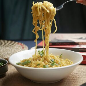 Close-up of freshly cooked noodles being lifted, garnished with herbs.