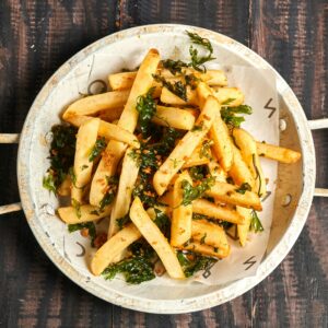 Crispy seasoned french fries with garlic and herbs in a rustic bowl.