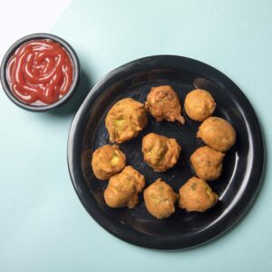 Delicious Indian pakoras served on a plate with ketchup, perfect for snack time.