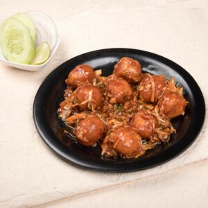 Tasty Manchurian balls served with cucumber, lime, and onions.