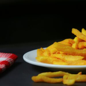 Close-up of crispy French fries on a plate with a red checkered napkin.
