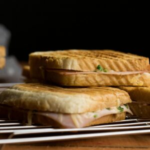 Close-up of freshly grilled sandwiches on a cooling rack, showcasing toasted bread and filling.