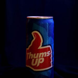 Refreshing close-up of a cold Thums Up soda can with dew droplets on a dark background.