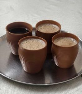 Four traditional clay cups with coffee and tea on a silver tray.