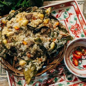 Authentic Vietnamese rice dish garnished with vegetables and chillies, served on decorative ceramic tableware.