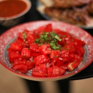 Close-up of a fresh tomato salad garnished with herbs, served in a decorative bowl.