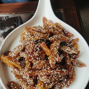 Delicious sesame-coated sweet potato sticks served on a white plate, perfect for a snack.